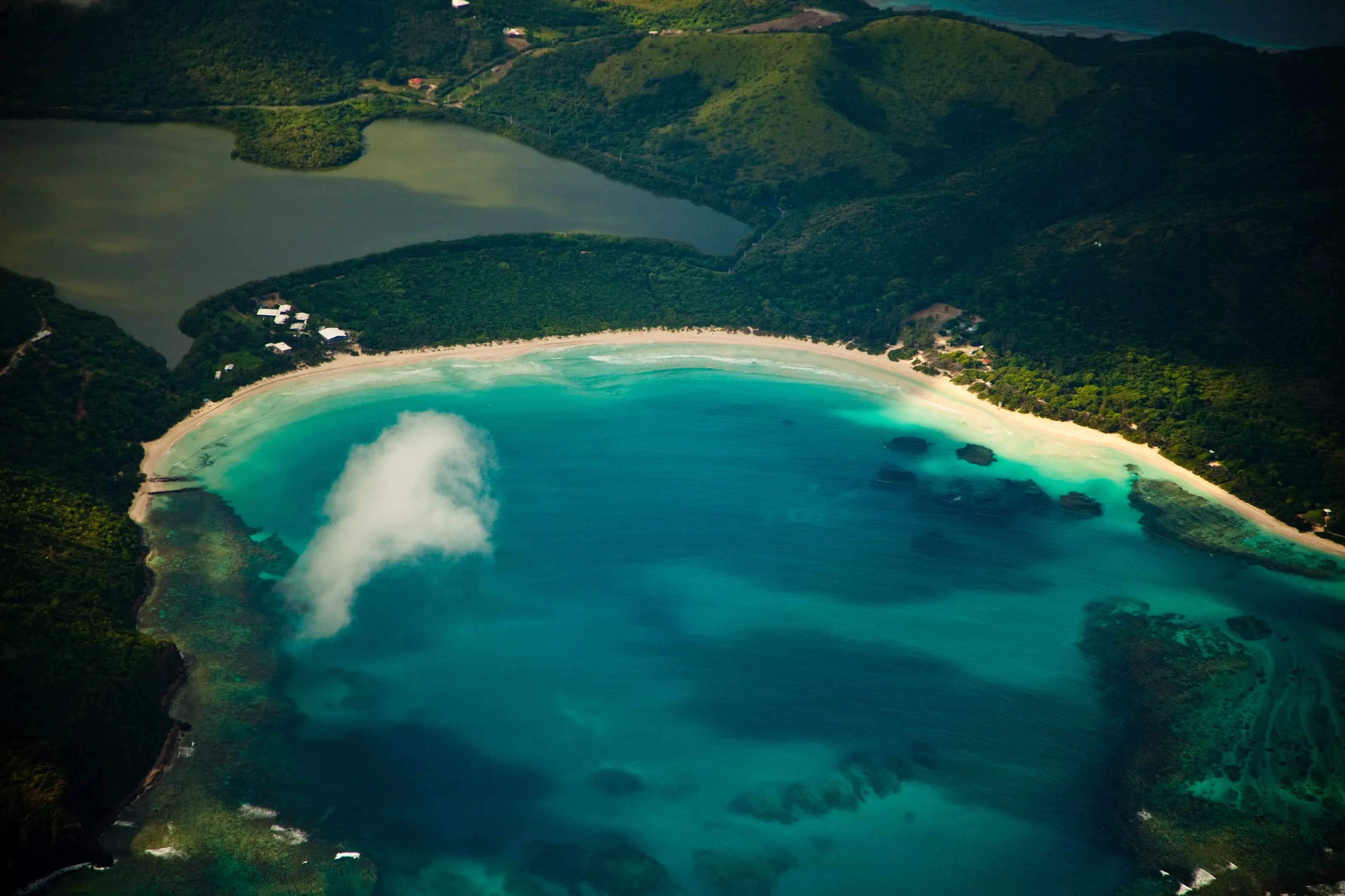 Flamenco Beach on Culebra, a long curve of white sand against clear turquoise water with low green hills behind